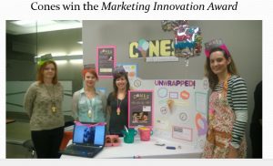 Four members of the team next to their booth containing information about product and promotional material