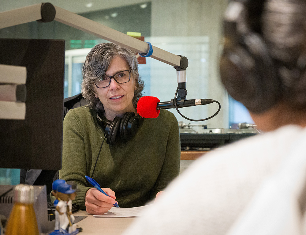 Photo of Dr. Martha Dow recording the CHASIcast in CIVL Radio's studio, taking notes and listening attentatively