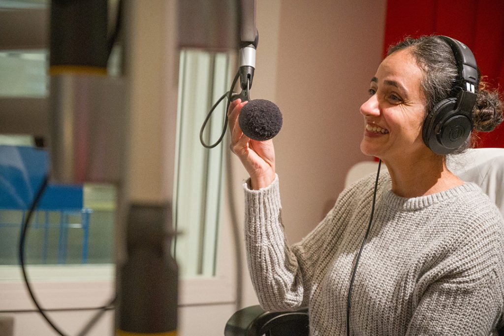 Photo of Dr. Sandhra speaking into a professional microphone in the CIVL Radio studies.