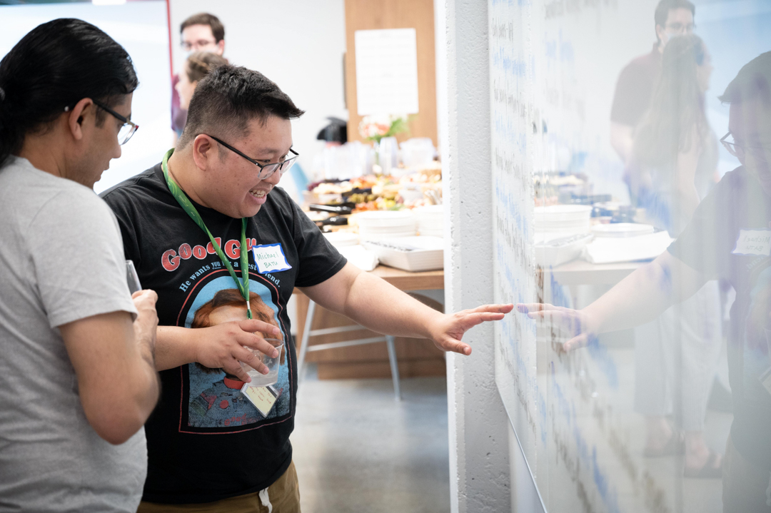 Dr. Michael Batu and Dr. Karun Karki enthusiastically discuss something written on a whiteboard