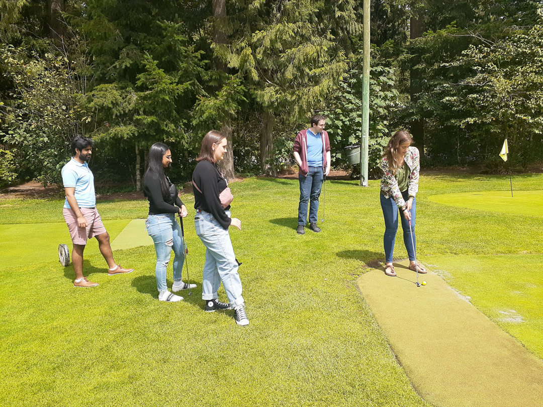 Photo of CHASI teams members watching Esther Jiménez Atochero lining up to hit a golf ball. 