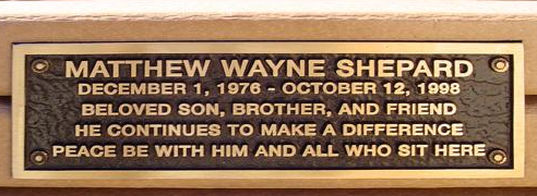 Photo of a bench plaque, which reads: "Matthew Wayne Shepard. December 1, 1976 – October 12, 1998. Beloved son, brother, and friend. He continues to make a difference. Peace be with him and all who sit here.