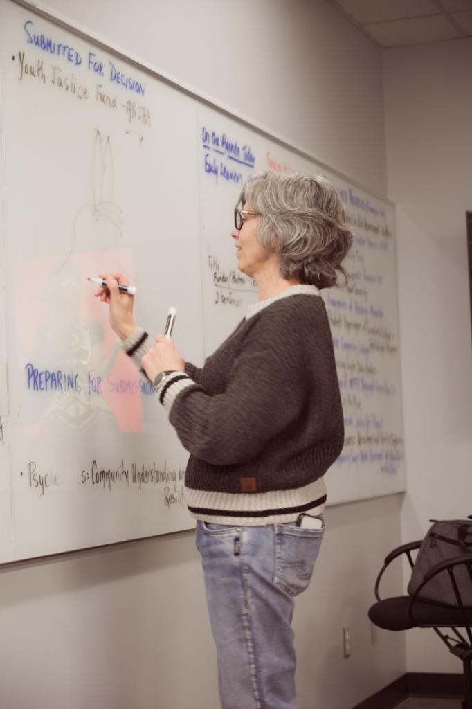 Photo of Martha Dow standing at a white board, drawing a picture of a rabbit.