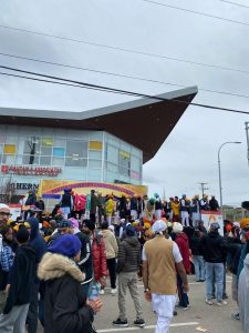 Images show large crowds at the Vaisakhi parade, musicians, performers, trucks and buses with celebratory signs, and booths and tends lining the street.