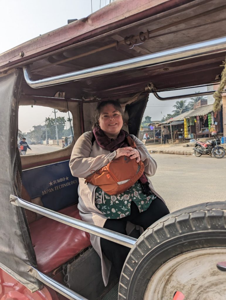 Photo of Allie smiling as she sits in the back seat of a rickshaw