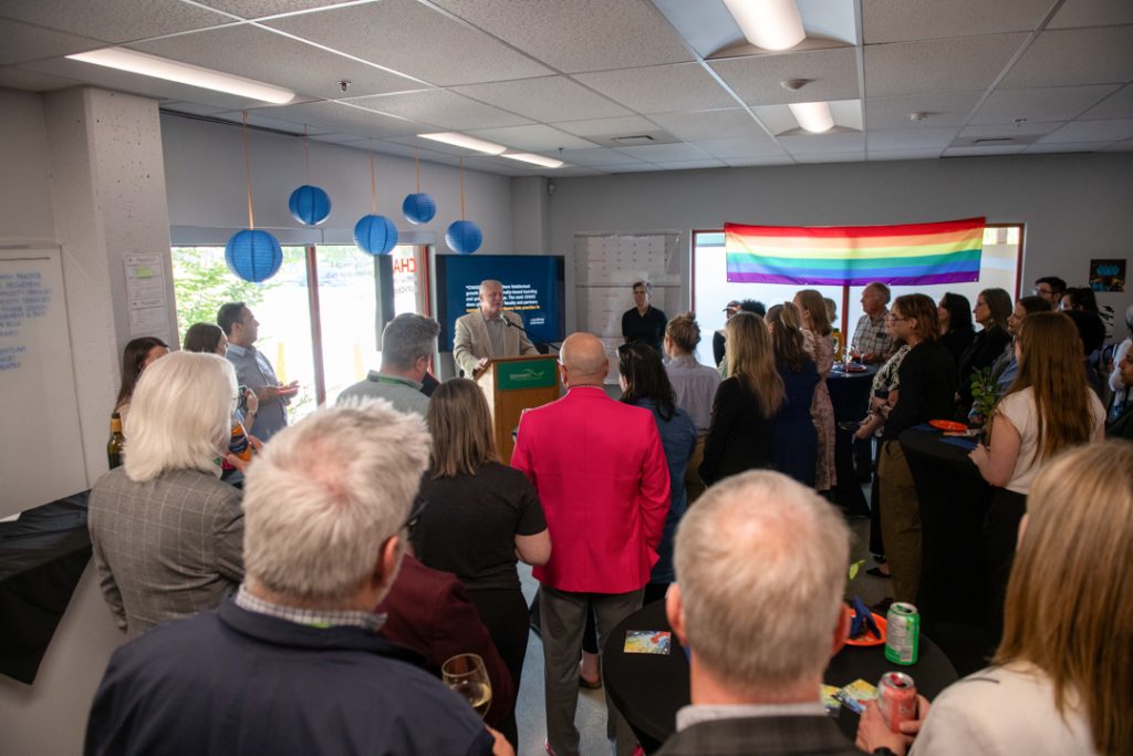 Photo of a crowd of people inside CHASI's office, standing to listen to a speech from Dr. James Mandigo