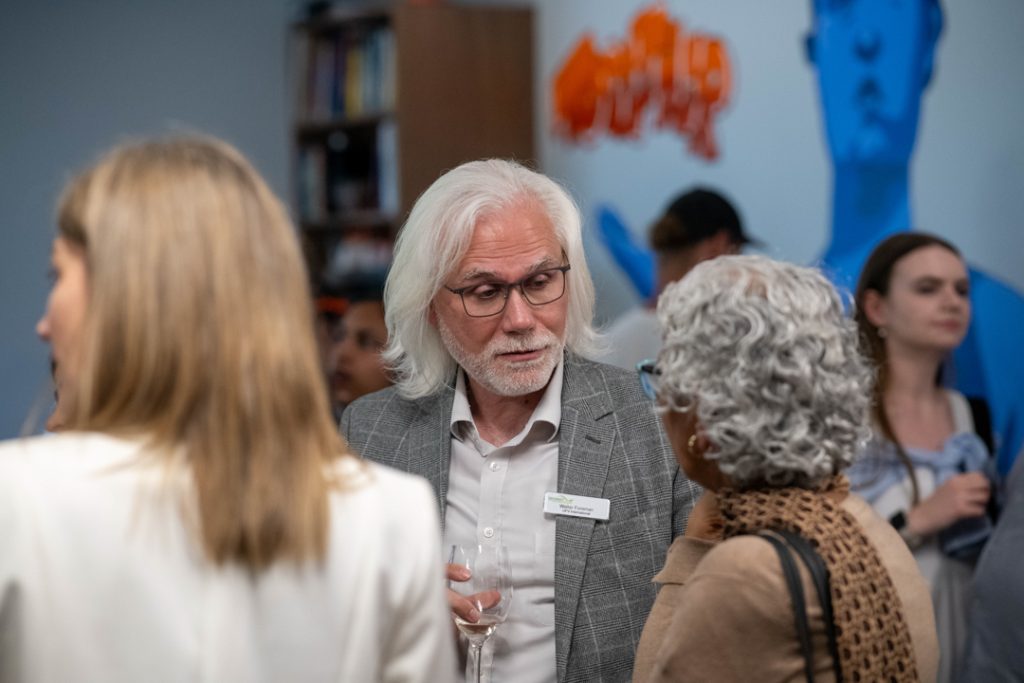 Walter Foreman speaks to Dr. Satwinder Bains amongst of a crowd of people at the event.