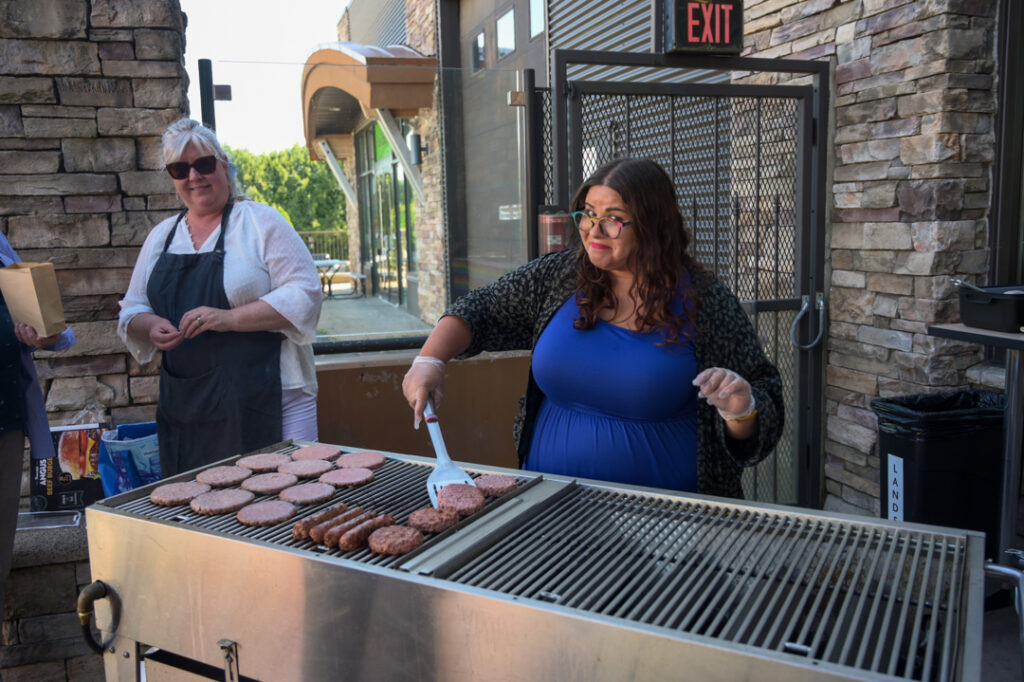Photo of volunteers preparing hamburgers and hot dogs on a barbecue.