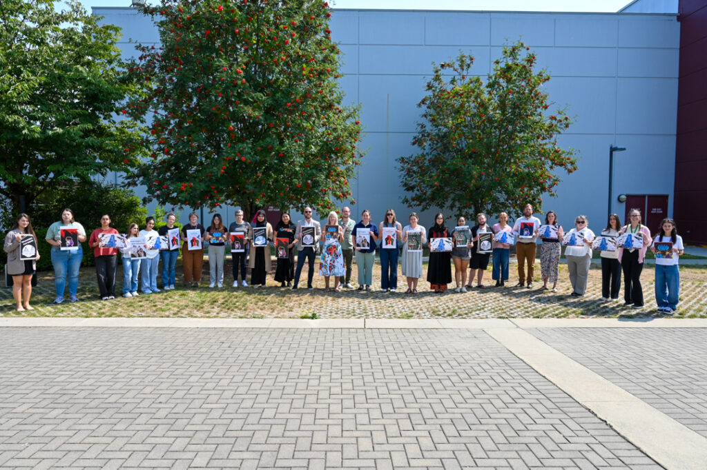 Photo of around 30 people standing in a line, holding up signs in support of people in Afghanistan.