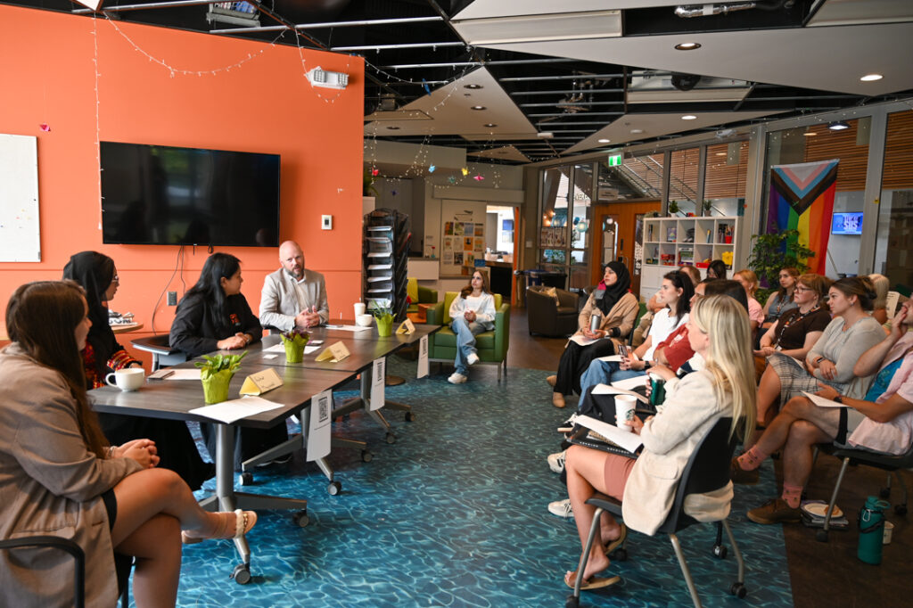 Photo of the room of the event, showing the panel, as well as a full audience