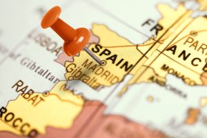 A paper map of Europe showing the country of Spain with a thumbtack pointing to Madrid.