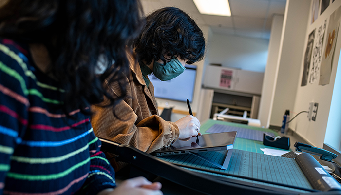 A UFV graphic design student hand draws using a tablet and stylus