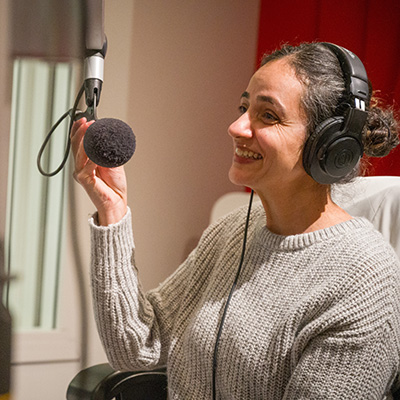 Photo of Dr. Sandhra speaking into a professional microphone in the CIVL Radio studies.