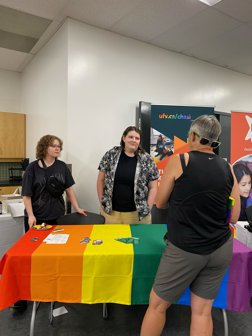 Photo of CHASI team members speaking at a table with a rainbow tablecloth.