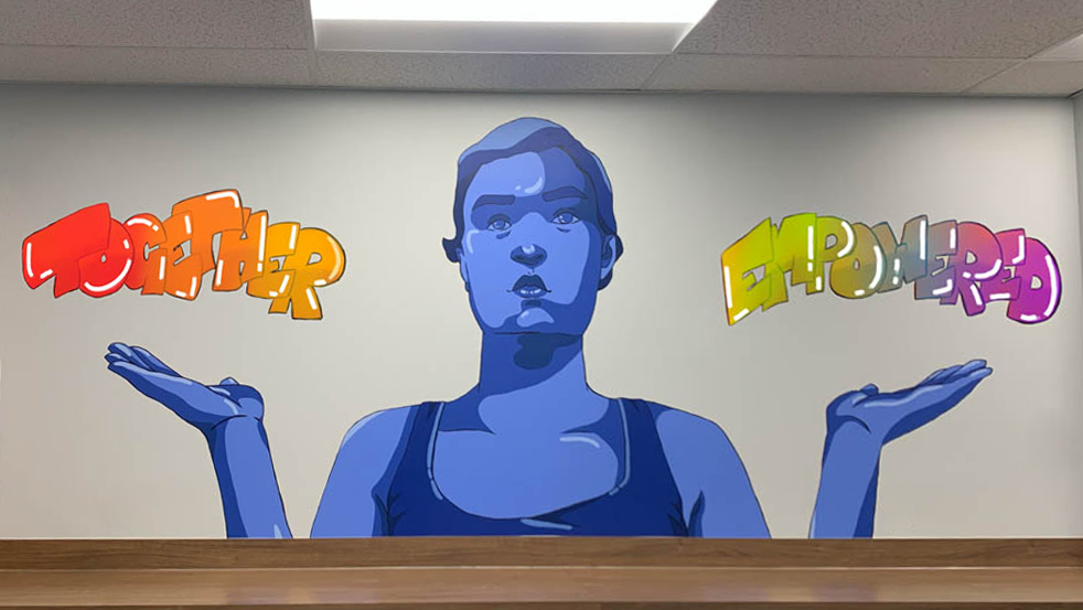 Photo of CHASI's wall mural, a large painting of a blue-toned person holding up their hands like scales. Above one hand is the word "together" and above the other is "empowered."