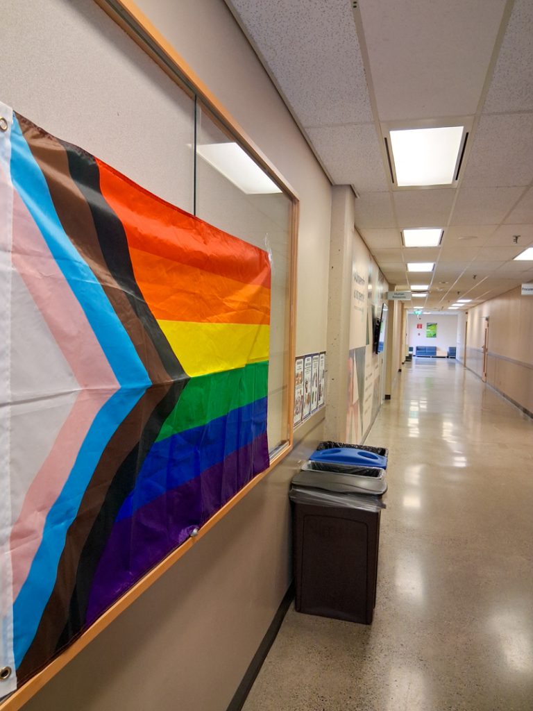 Photo of a pride flag on a display case in a hallway at UFV