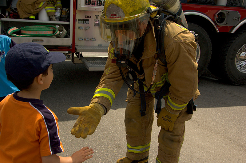 Stock photo of a firefighter extending a hand to a young child.