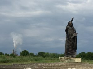 Standing Bear Monument with refinery stacks in the background