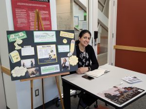 Navneet Sidhu sitting at an SLG display