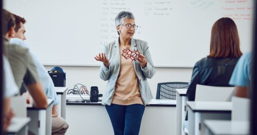 Teacher at the front of a classroom facing the class