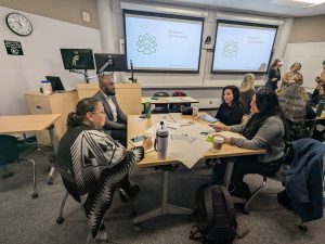 4 attendees sitting at a table discussing a topic