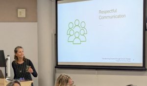 Theresa standing next to a projector screen displaying "Respectful Communication"