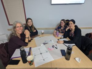 4 people sitting at a table looking at the camera smiling