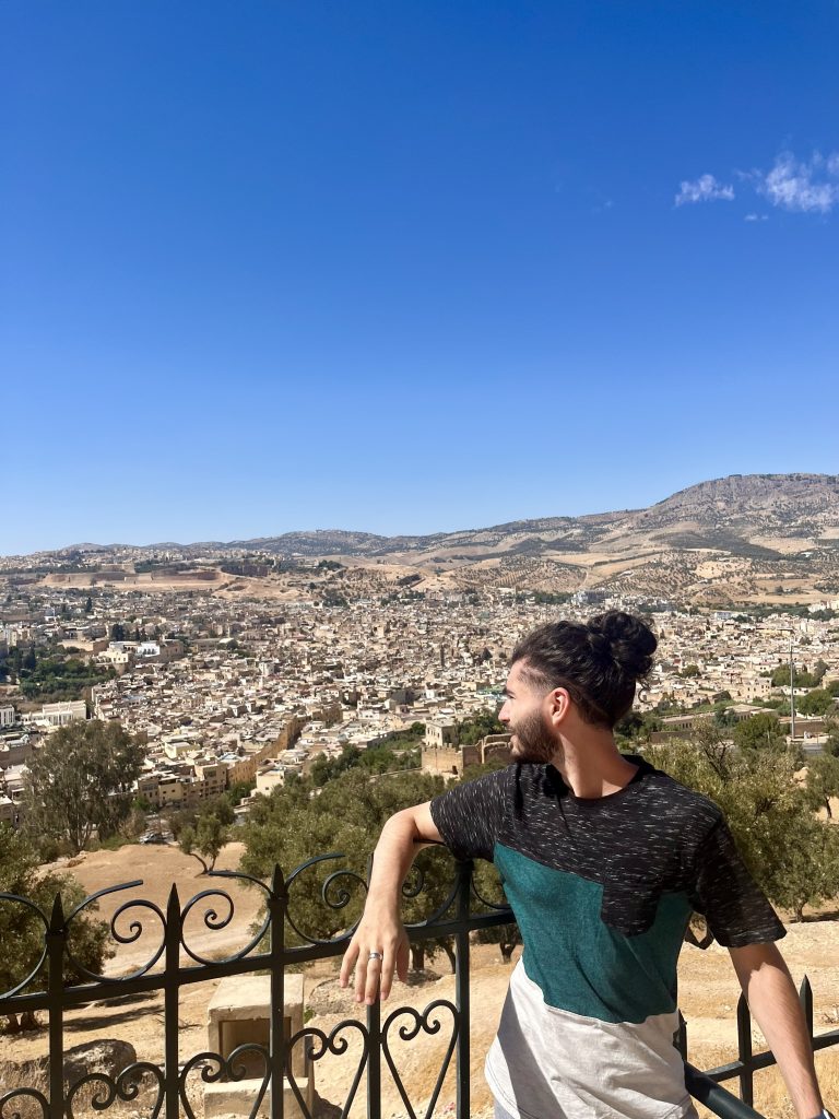 Ahmed leaning up against a railing looking out to the city of Morocco below