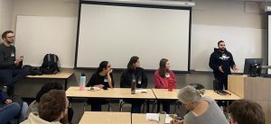 a panel of SLG leaders is facing a classroom with 1 leader standing up looking at the class