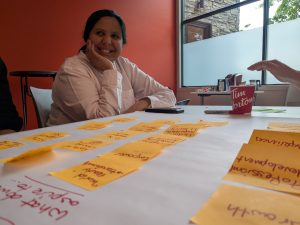 Learning Designer, Fizza, smiles at the camera with a bunch of yellow post-it notes in front of her.