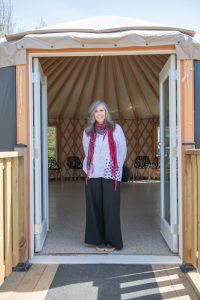 Dr. Christine Slavik, associate professor at faculty of Child, Youth, 7 Family Studies, standing in front of the entrance to a yurt, a portable, round tent covered and insulated with skins or felt and traditionally used as a dwelling by several distinct nomadic groups