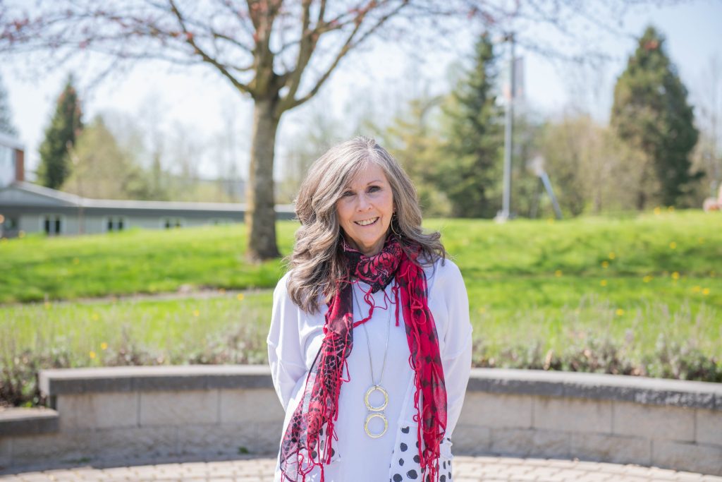 Dr. Christine Slavik, associate professor at faculty of Child, Youth, 7 Family Studies, standing in front of the labyrinth on the University of the Fraser Valley Abbotsford campus